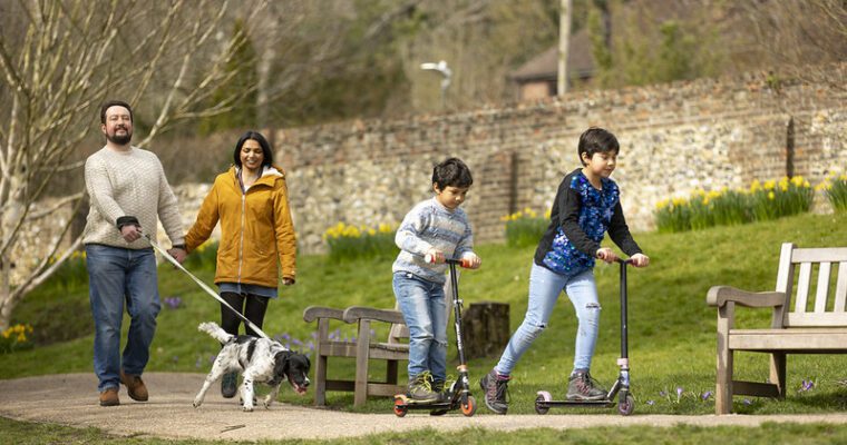 Children ride their scooters at Kearsney Abbey while their parents follow with the dog.