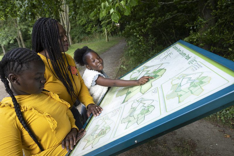 Mum and daughters look at the map of Capstone Farm Country Park.