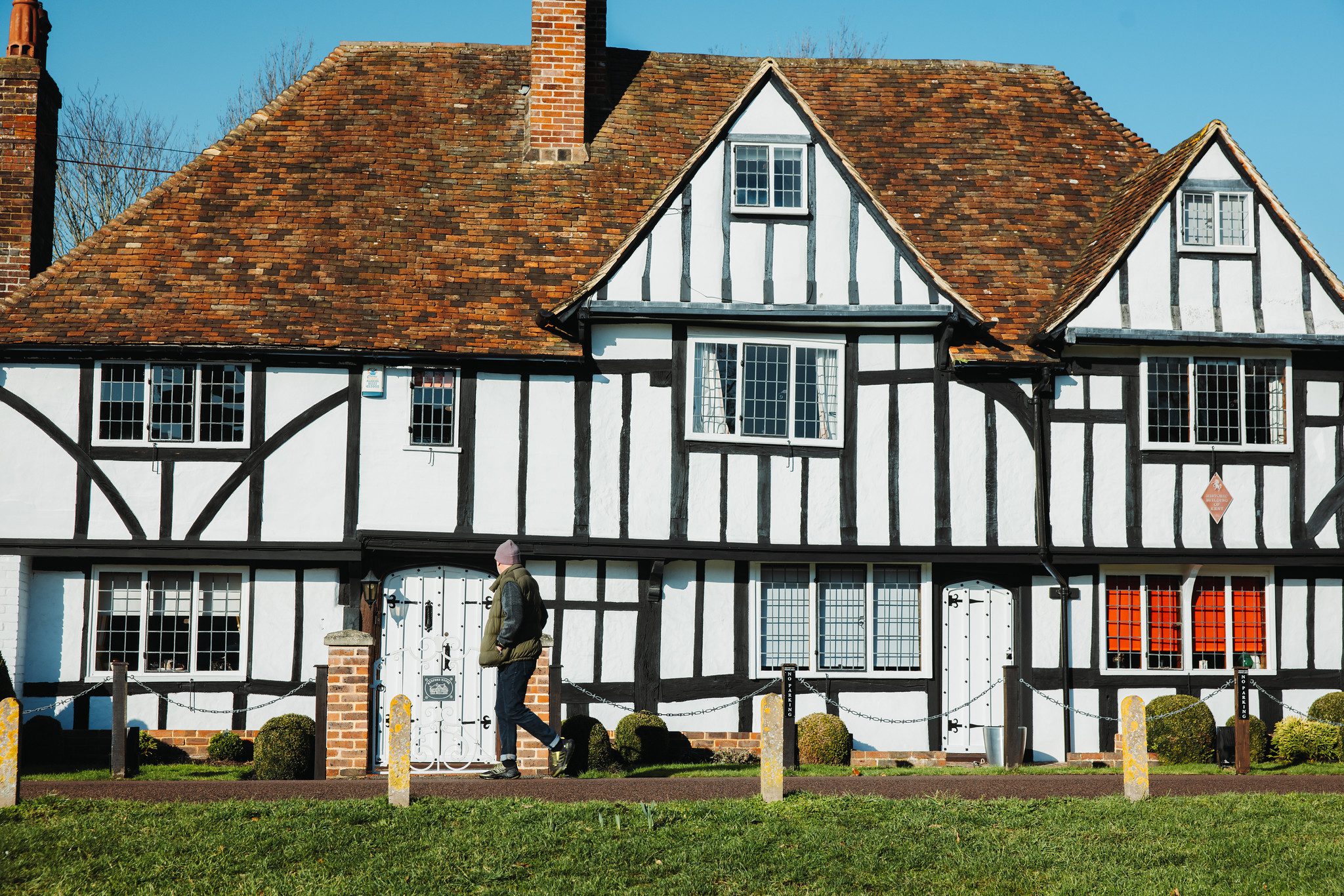 Man walking in front of tudor-style house