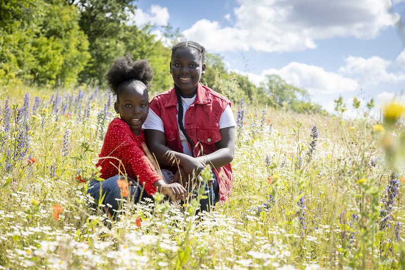 Two girls sit in the wildflower fields at Ranscombe Farm.