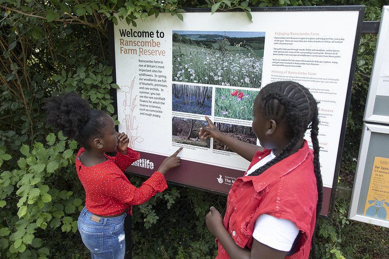 Two girls read the information board at Ranscombe Farm.