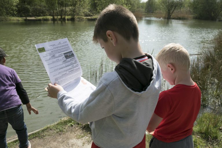 Two Young Boys looking at Maps by a River