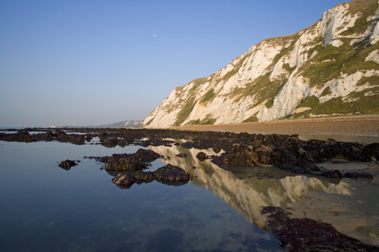 View of the sea with the cliff reflecting in the water