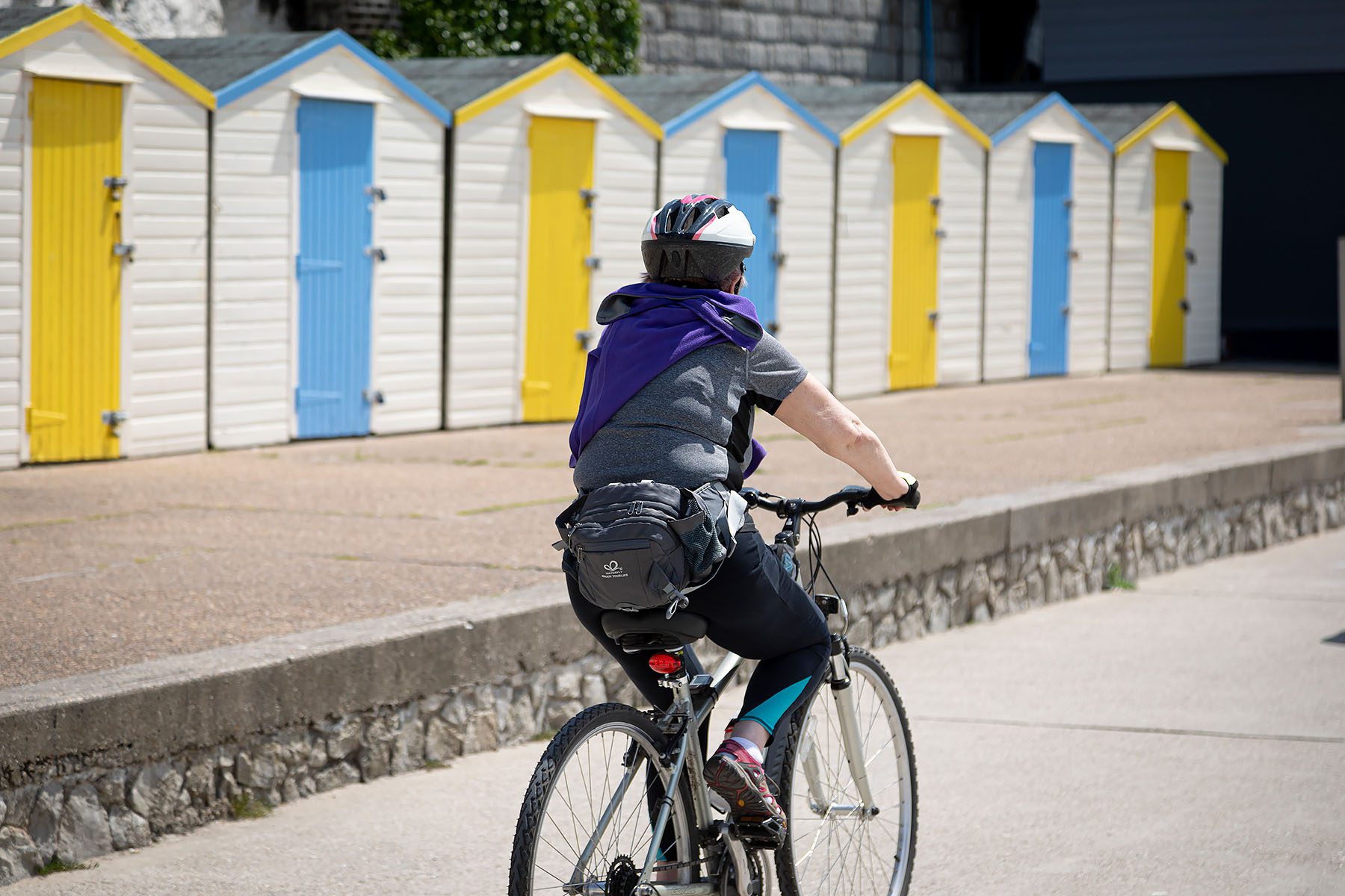 womens cycling past colurful beach huts at westgate on sea