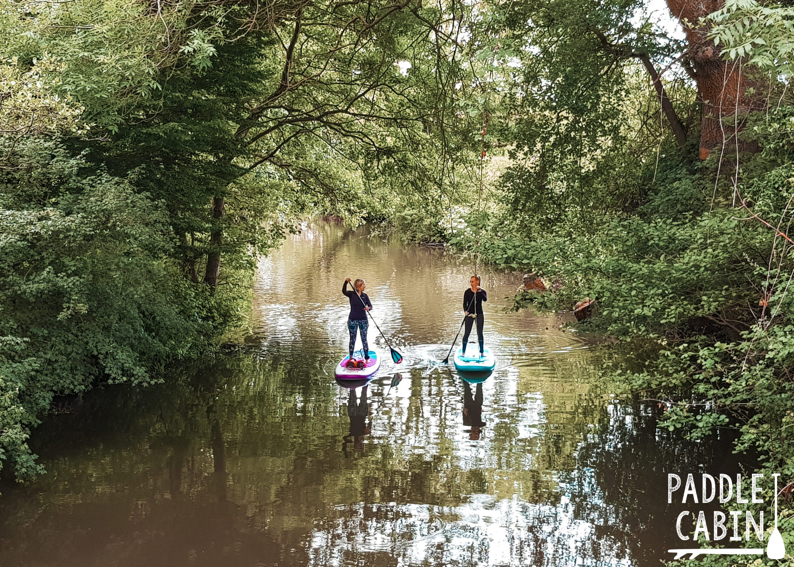 Two women paddle boarding on the river Medway