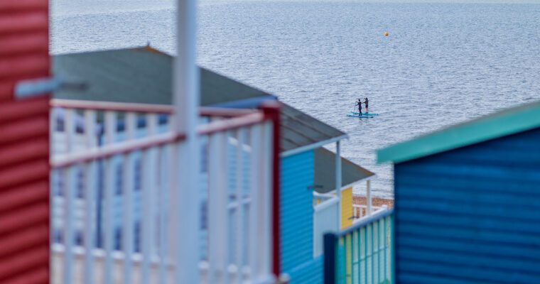 paddleboarders out to sea inbetween tankerton beach huts