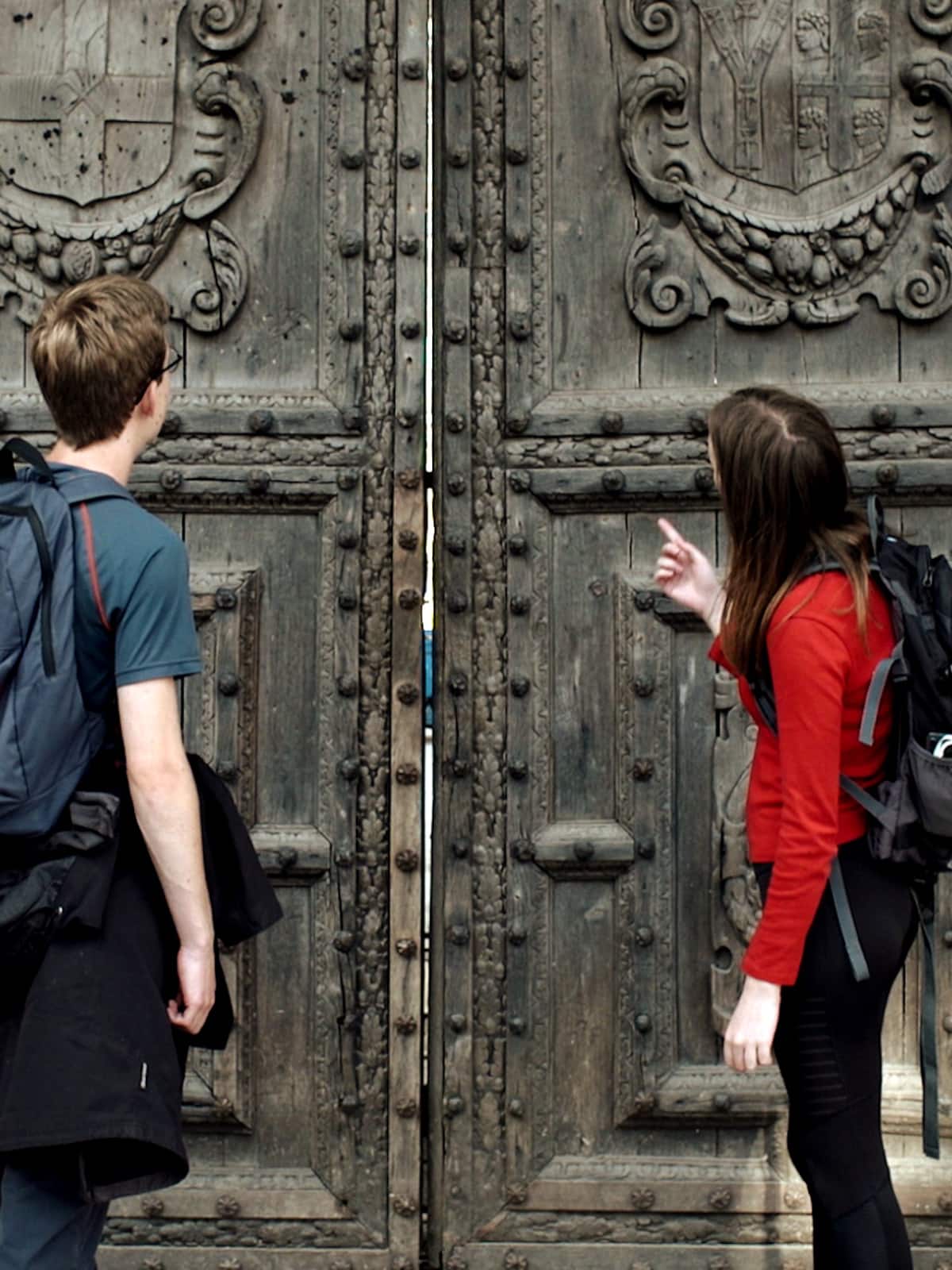 Two people outside a large ancient door
