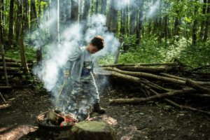 Boy learning how to make a fire in the woods