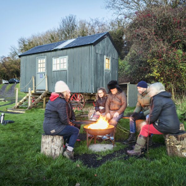 Greenhill Glamping shepherds hut with family gathered around campfire