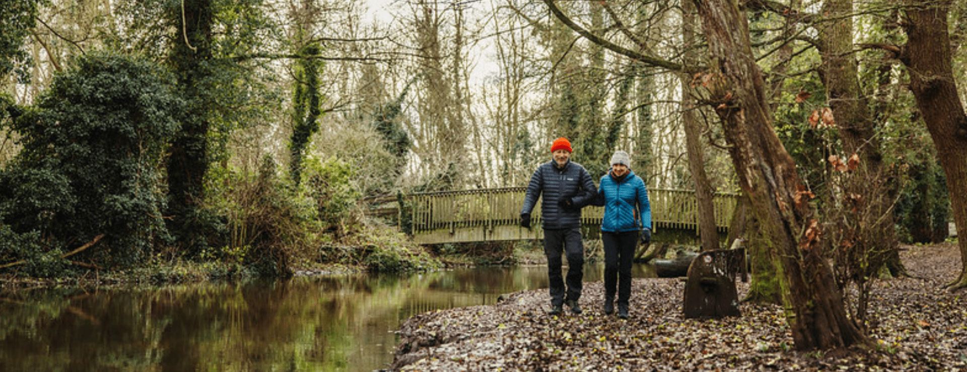 A couple walking alongside the River Darent at Lullingstone on a chilly, autumnal day