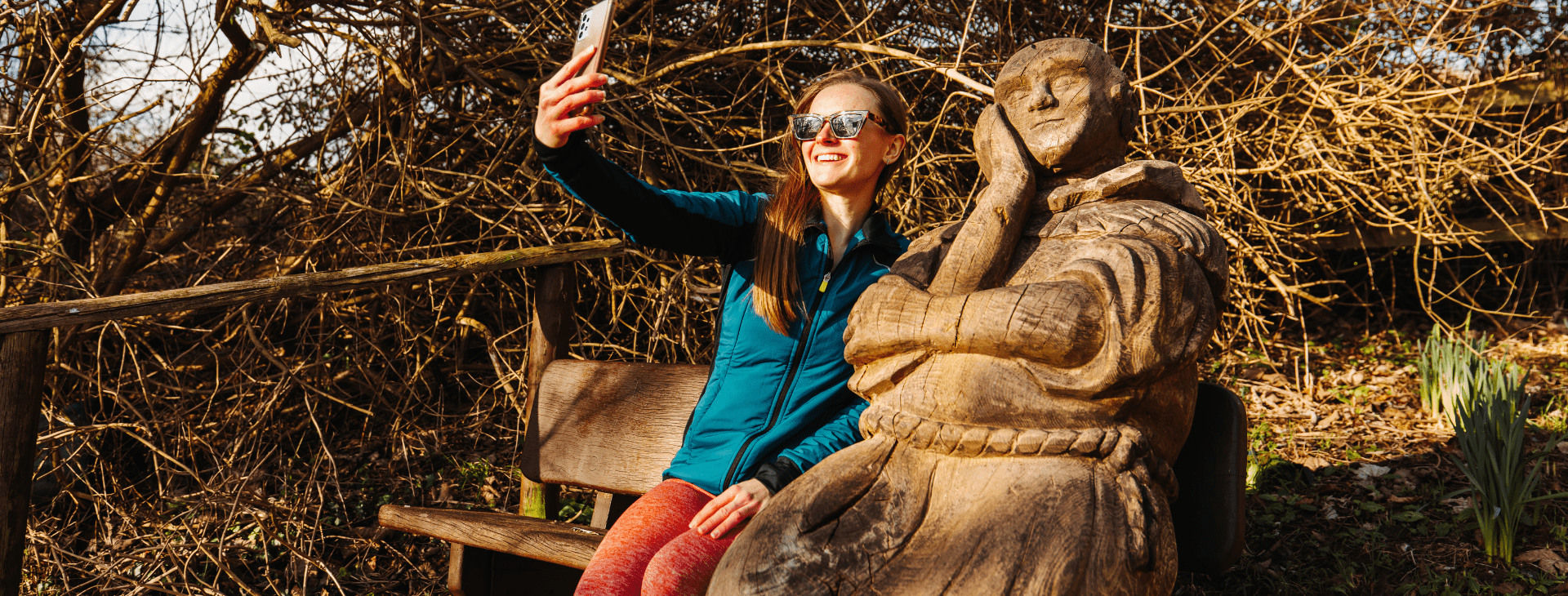 Female taking a selfie with Percy the Pilgrim, a statue on the bench