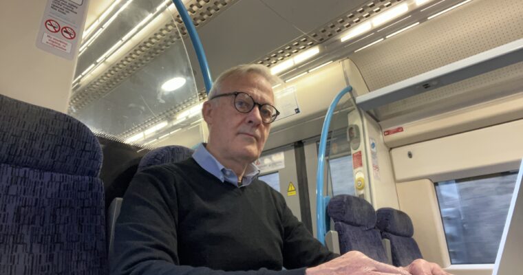 Man sitting on a train with a laptop