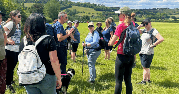Group of walkers standing in a field listening to the walk leader