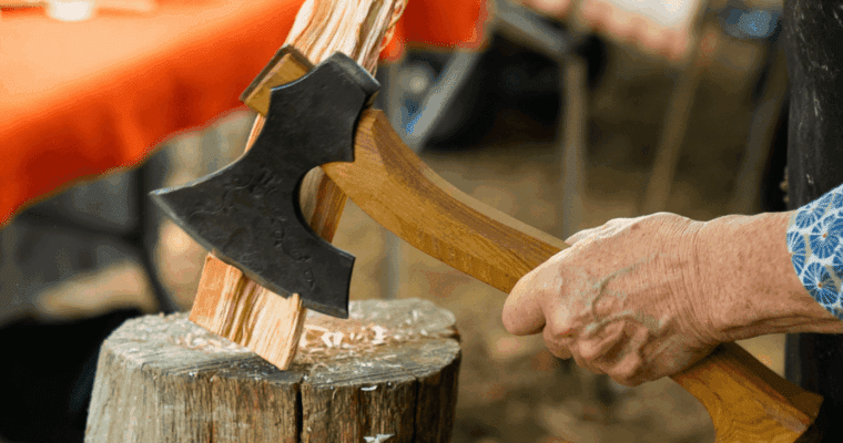 A hand holding an axe chopping wood