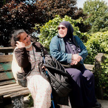 Two females sitting on a bench smiling