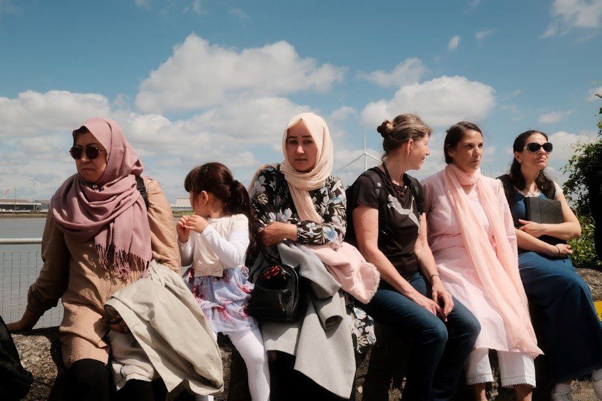 A group of females sitting on a wall.