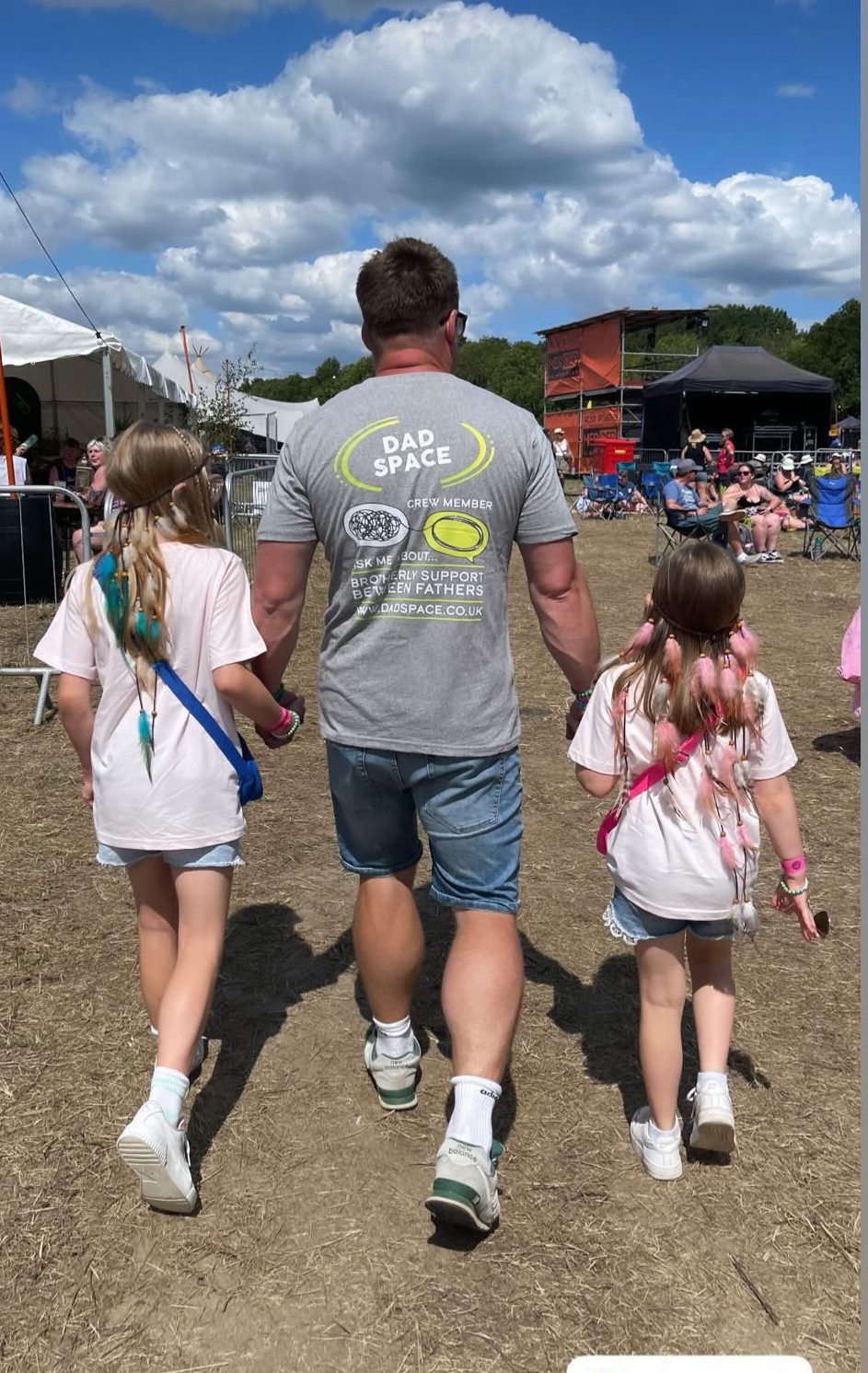 A dad walking with his two daughters. They have their backs to the camera and the dads tshirt says Dad Space