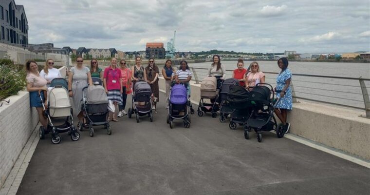 Pushchairs and mums from the bump club lined up for a photo next to a river