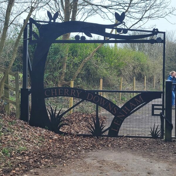 A black metal fence in shape of a tree branch with the words Cherry Downs Lenham