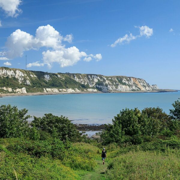 Person walking towards the sea with white chalk cliffs in the background, Folkestone Warren Nature Reserve