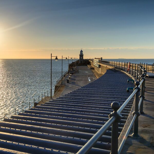 Folkestone Harbour Arm next to the sea with the sun low in the sky.