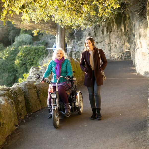 A woman walking next to another woman in a wheelchair down a slope, Lower Leas Coastal Park Folkestone
