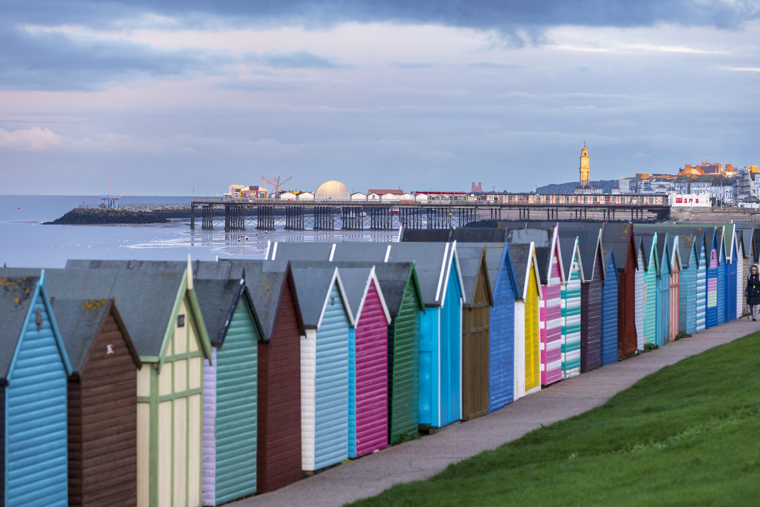 close up image of colourful beach huts. Can see Herne Bay pier in the distance