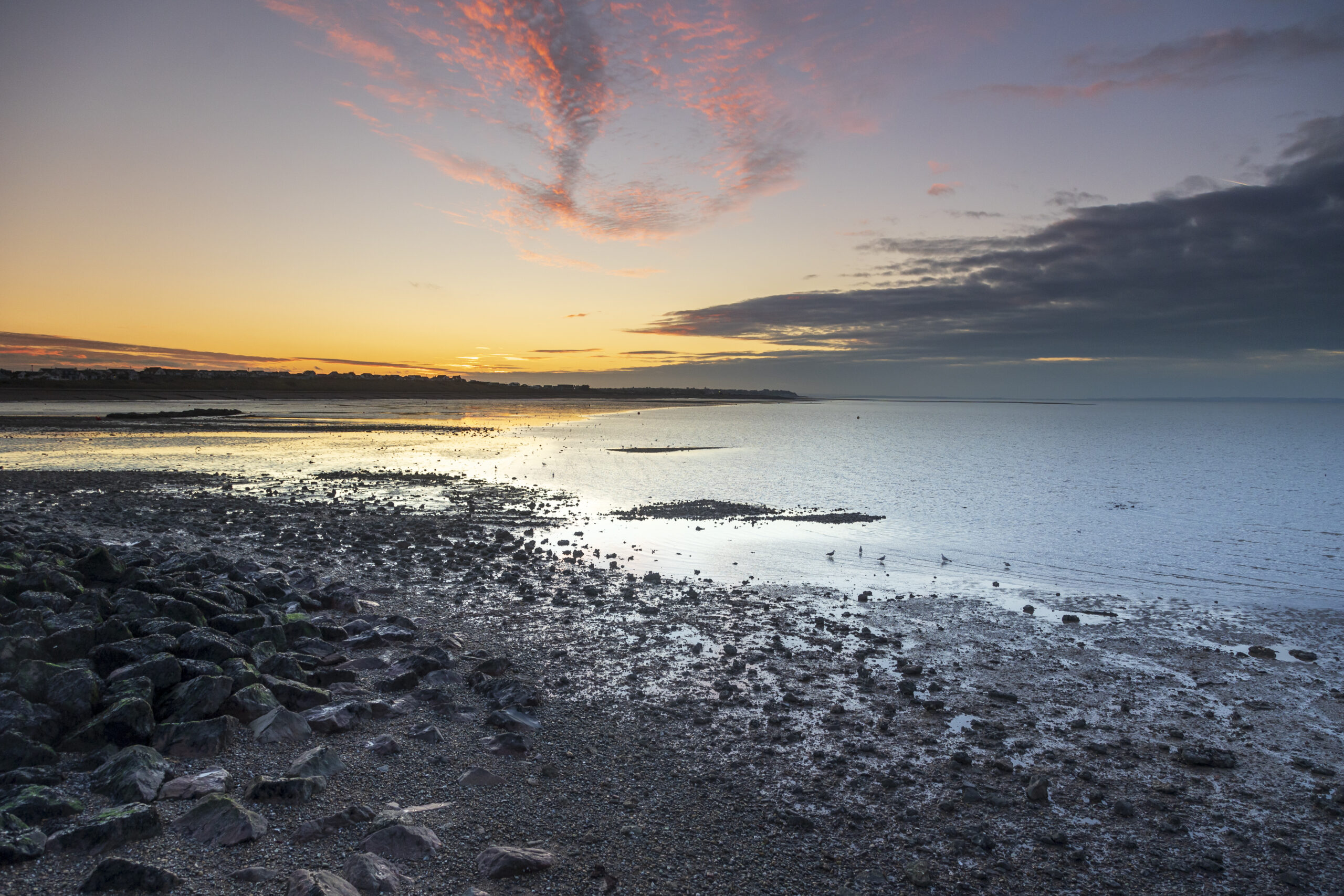 sun setting with the sea and a pebble beach