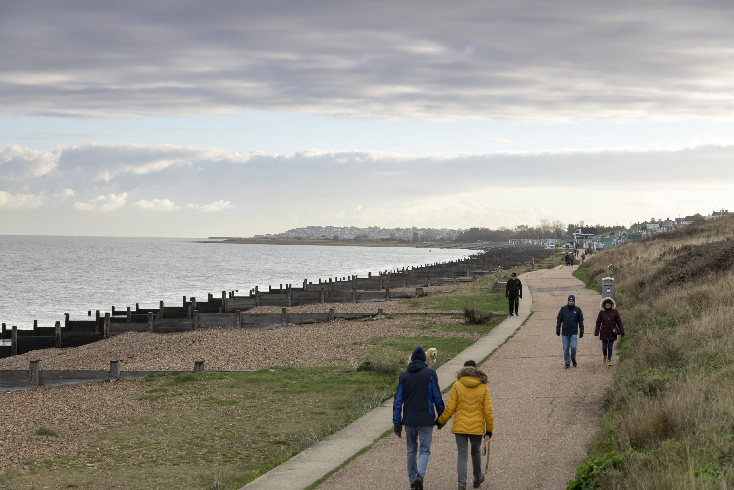 walkers on a path beside the sea