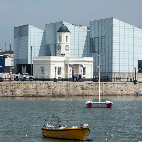 Turner Contemporary and Margate visitors centre next to the harbour with several small boats in the water.
