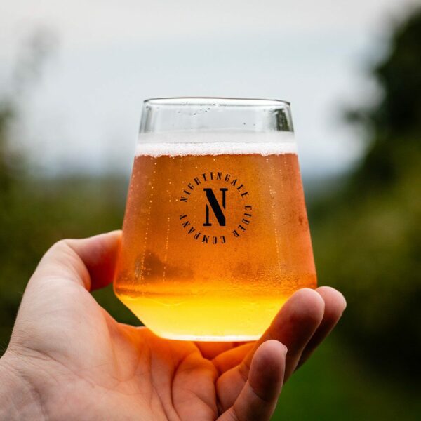 A person holding a Nightingale Cider glass.