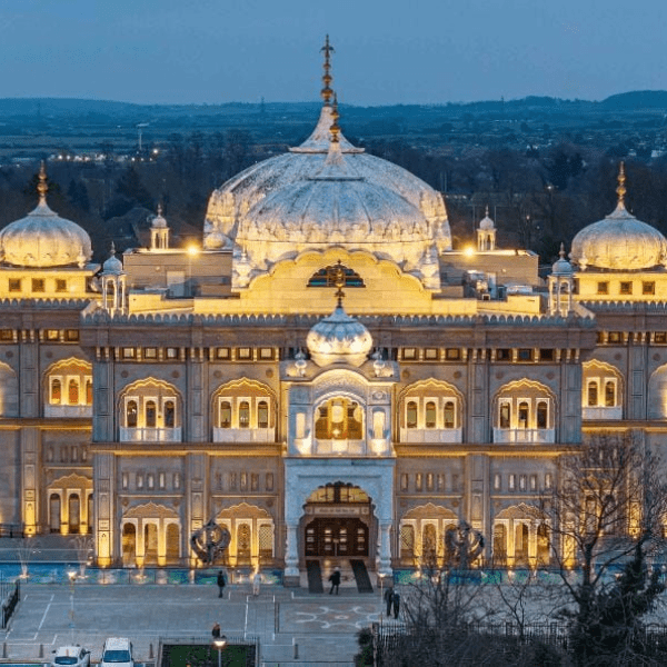The outside of a Gurdwara (Sikh Temple) lit up at dusk.