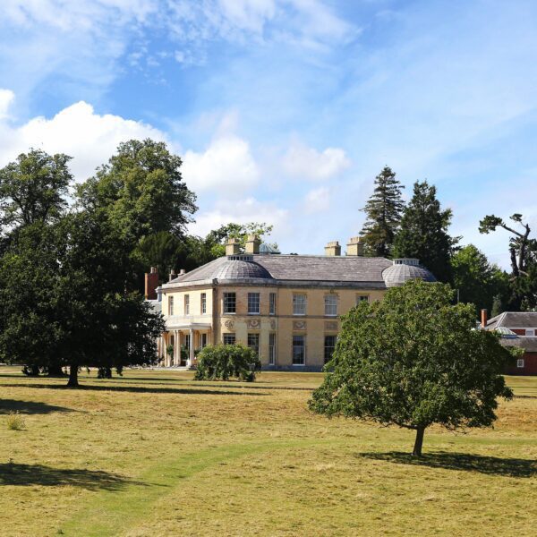 A stately home surrounded by grass with trees.