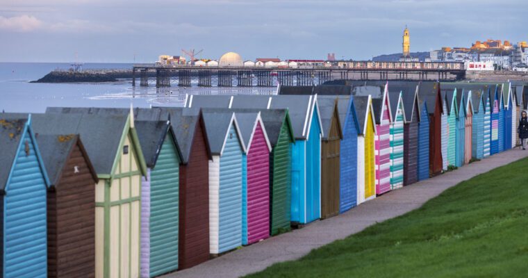 close up image of colourful beach huts. Can see Herne Bay pier in the distance