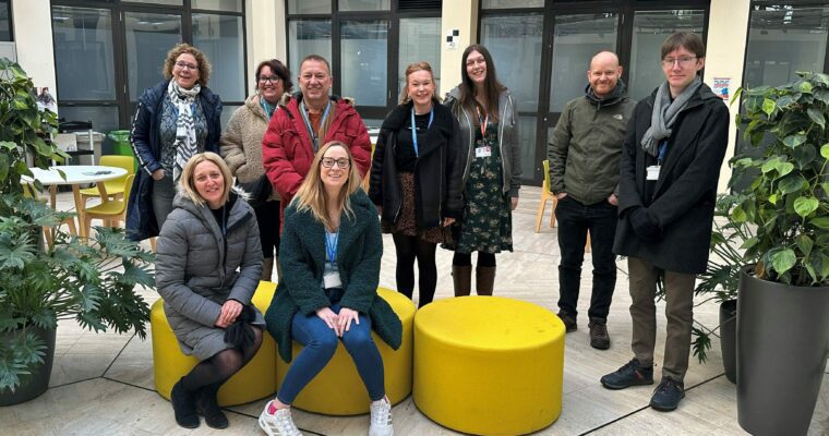 A group of people wearing coats in an office before going on a wellbeing walk.