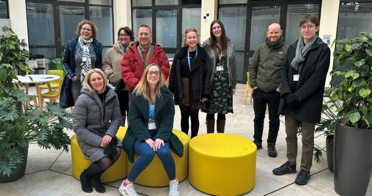 A group of people wearing coats in an office before going on a wellbeing walk.