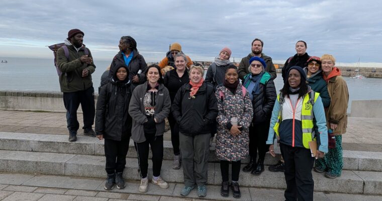 A group of people standing by some steps by the sea.