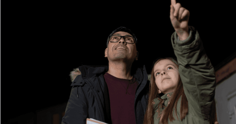 A father and daughter at night looking at the sky.