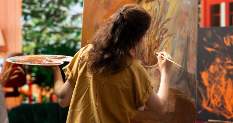 Lady painting on a canvas with expressive orange colours