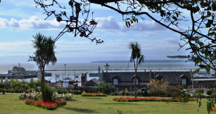 Large green garden space, with colourful flower beds, overlooking sea