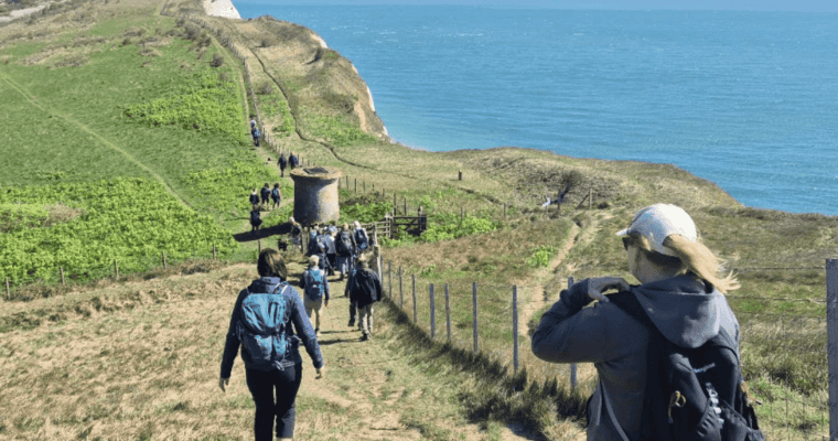 A group of walkers walking along the cliffs in Dover with the sea to their right