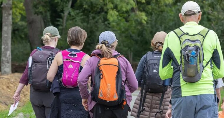 5 people wearing backpacks heading on a walk