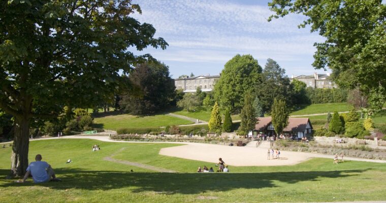 People sitting on the grass with a cafe and walking paths in the background in Calverley Park, Tunbridge Wells